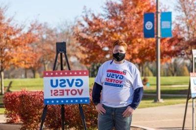 Student standing in front of a GVSU Votes sign